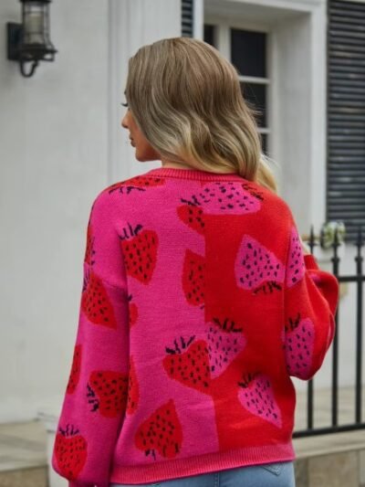 woman turned to her back wearing colorful strawberry cardigan, white house in the backgorund