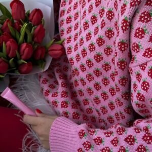 woman wearing colorful strawberry sweater exposing its material and holding roses and a pink pen