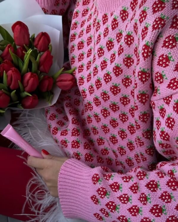 woman wearing colorful strawberry sweater exposing its material and holding roses and a pink pen