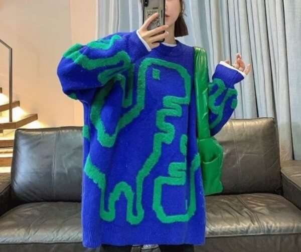 woman wearing colorful streetwear sweater and a green bag, she is holding a phone