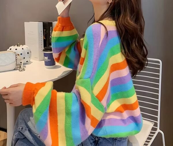 woman turned to her side wearing colorful striped sweater and sitting on a white chair