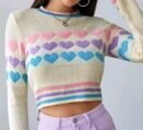 woman wearing colorful sweater with hearts and lifting one hand up
