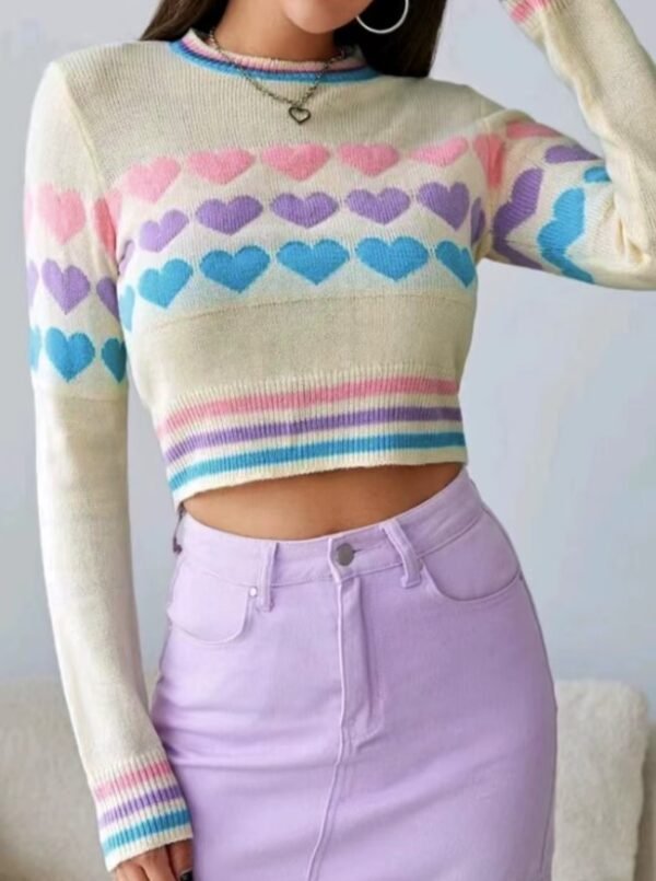 woman wearing colorful sweater with hearts and lavender pencil skirt, white wall behind her