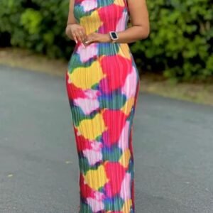 woman wearing colorful tie dye dress, a street and bushes behind her