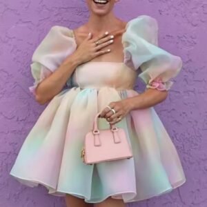 woman wearing colorful tulle dress and holding a pink bag, purple wall behind her