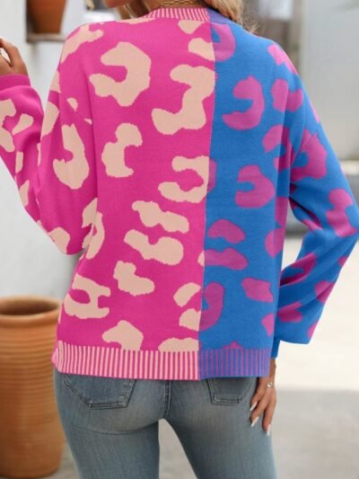 woman turned to her back wearing colorful two-sided cardigan and grey jeans, white room in the background