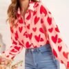 woman wearing colorful valentines blouse and jean, she is holding flowers