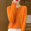 woman wearing orange colorful wool sweater and white pants