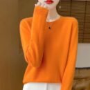 woman wearing orange colorful wool sweater and white pants