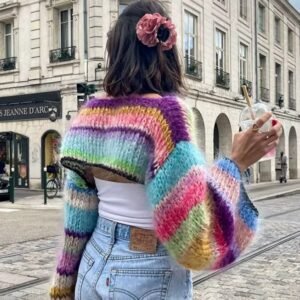 woman turned to her back wearing cropped colorful sweater and having a pink scrunchie in her hair, the street in the background