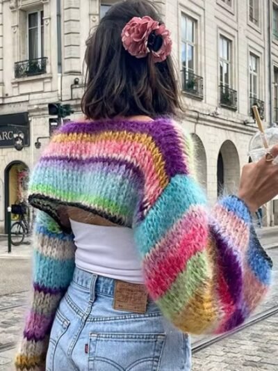 woman turned to her back wearing cropped colorful sweater and having a pink scrunchie in her hair, the street in the background