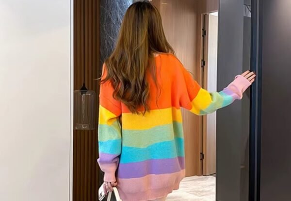 woman turned to her back wearing cute colorful sweater, an apartment behind her