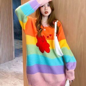 woman posing in cue colorful sweater, she has one hand up and she has a white bag over the other one