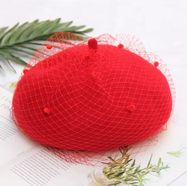 elegant colorful beret on the white table, a green leaves next to it