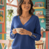 woman with short brown hair wearing elegant colorful sweater and holding a white cup