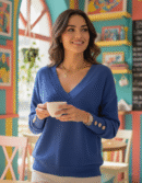 woman with short brown hair wearing elegant colorful sweater and holding a white cup