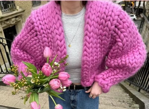 woman wearing fuchsia cardigan, white top and holding a bouquet of roses