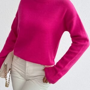 woman turned to her side wearing fuchsia sweater and white jeans, she is holding a white purse