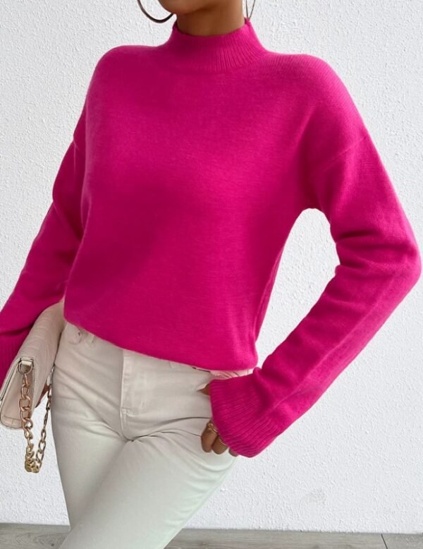 woman turned to her side wearing fuchsia sweater and white jeans, she is holding a white purse