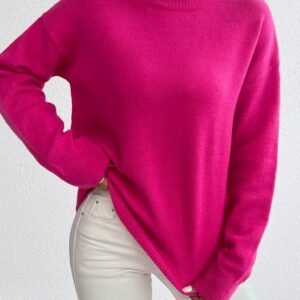 woman wearing fuchsia sweater and white jeans, white wall in the background