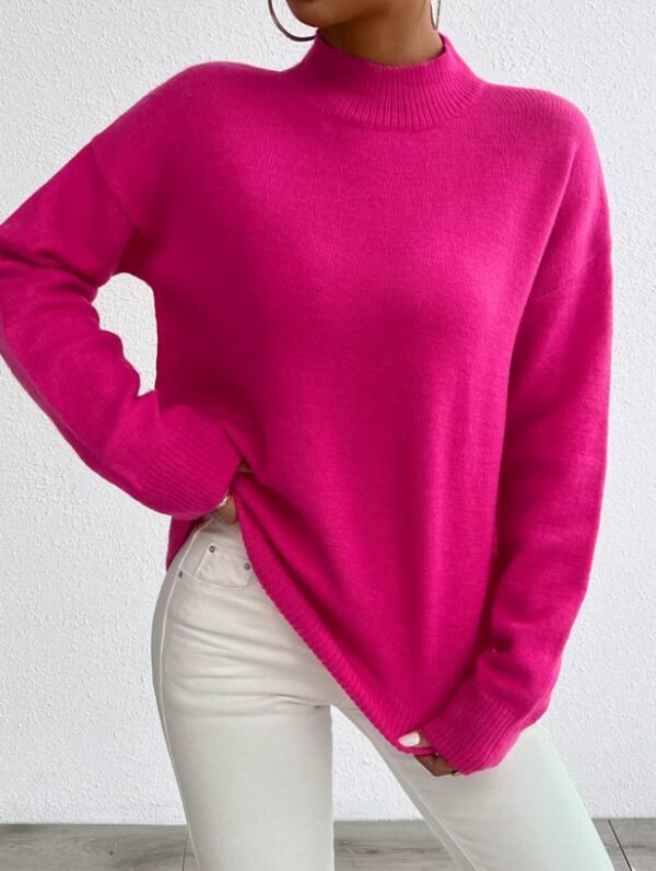 woman wearing fuchsia sweater and white jeans, white wall in the background