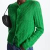 woman wearing green cardigan and carrying a black purse