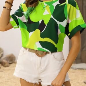 woman wearing green colorful blouse and white shorts, sand in the background