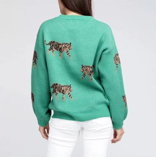 woman turned to her back wearing green colorful tiger print sweater and white pants