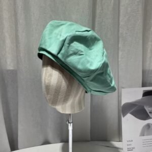 colorful womens beret on a mannequin, grey curtains in the background