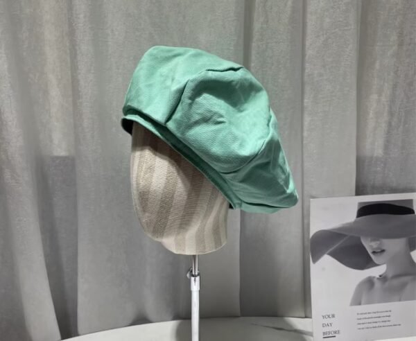 colorful womens beret on a mannequin, grey curtains in the background