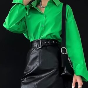 woman wearing green oversized colorful blouse and black pencil skirt, black backgound