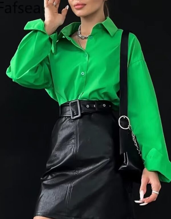 woman wearing green oversized colorful blouse and black pencil skirt, black backgound