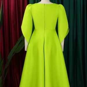 back view of modest colorful dress on a mannequin, red and green curtain in the background