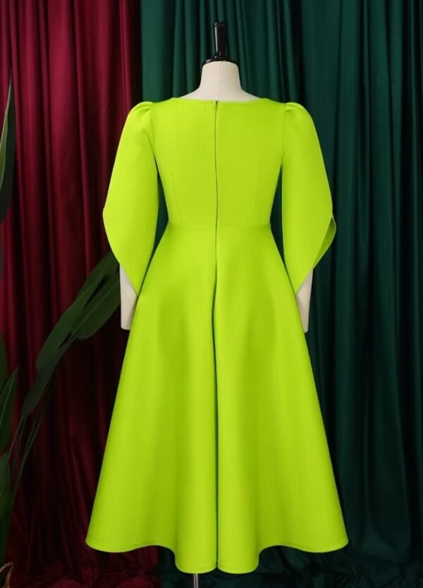 back view of modest colorful dress on a mannequin, red and green curtain in the background