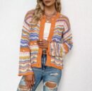 woman wearing multicolor cardigan and jeans, white wall in the background