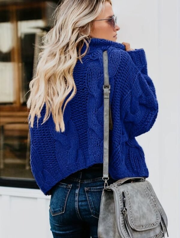 woman with blonde hair turned to her back wearing navy blue colorful sweater and a grey bag