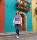 woman with brown hair side wearing old-fashion sweater and jeans, colorful buildings in the background