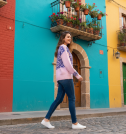 woman turned to her side wearing old-fashion sweater and jeans, colorful buildings in the background