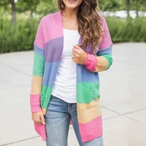 woman wearing pastel cardigan and a white top under it, grey alley and grass in the background