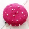 pink beret with pearls lying on the white table, pieces of paper around it