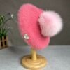 pink colorful beret with a pompom on the wooden pillar, grey table in the background