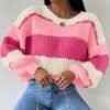 woman wearing pink colorful sweater and jeans, white wall behind her