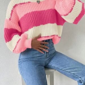 woman sitting on a white chair and wearing pink colorful sweater, jeans and a silver necklace