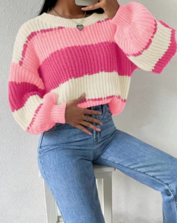 woman sitting on a white chair and wearing pink colorful sweater, jeans and a silver necklace