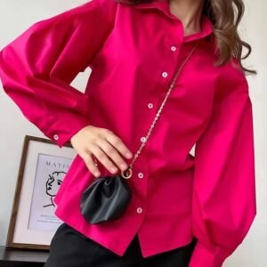 woman wearing pink oversized colorful blouse, black pants and a black purse