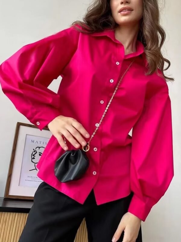 woman wearing pink oversized colorful blouse, black pants and a black purse