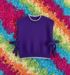 purple colorful sleeveless sweater placed on a colorful carpet