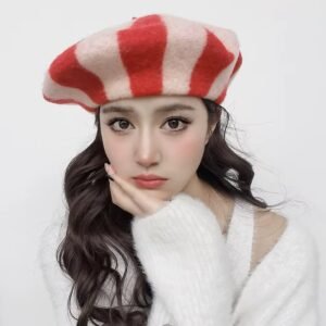 woman with dark brown hair wearing red colorful striped beret and a white sweater