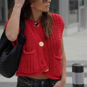 woman wearing red sleeveless cardigan, jeans and holding a black bag