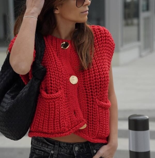 woman wearing red sleeveless cardigan, jeans and holding a black bag